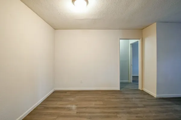 a view of an empty room with wooden floor and closet