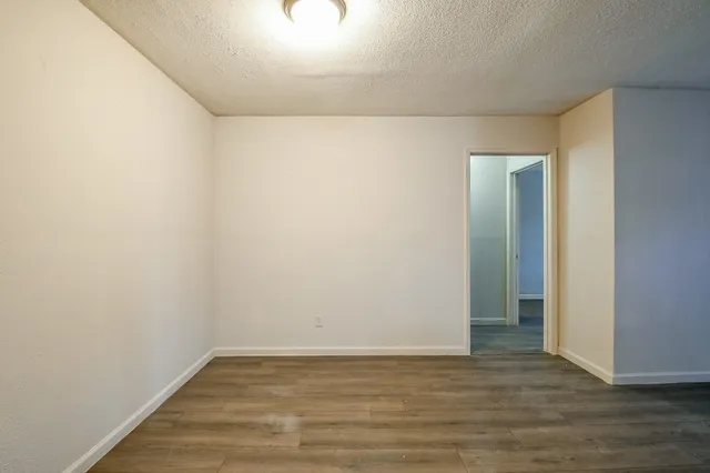 a view of an empty room with wooden floor and closet