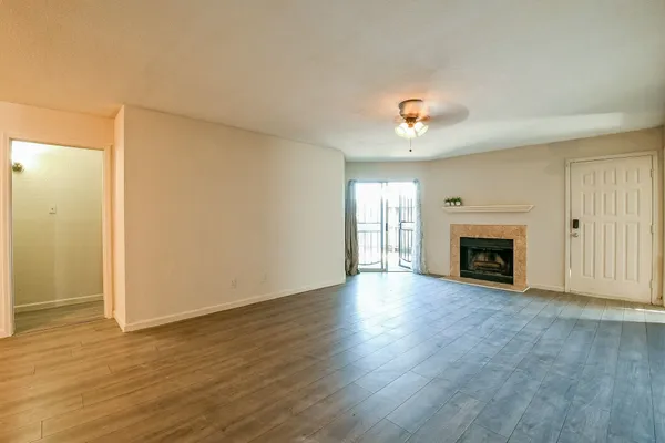 an empty room with wooden floor fireplace and windows