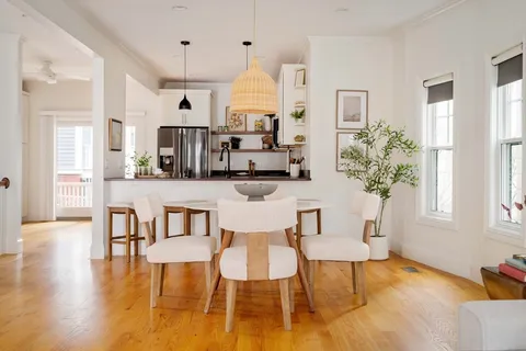 a living room with stainless steel appliances kitchen island granite countertop furniture and a wooden floor
