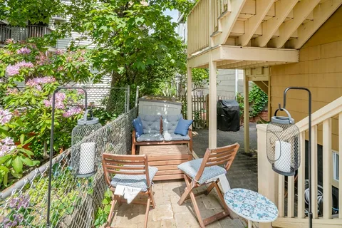 a patio with table and chairs and potted plants