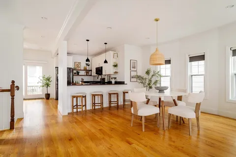 a view of a dining room and livingroom with furniture wooden floor a chandelier