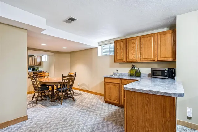 a kitchen with stainless steel appliances granite countertop a table chairs sink and cabinets