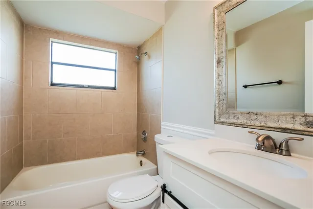 a bathroom with a granite countertop bathtub shower sink vanity mirror and toilet
