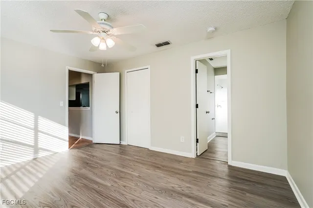 an empty room with wooden floor and ceiling fan