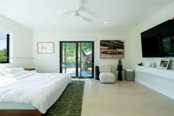 a spacious bedroom with a bed and a flat screen television