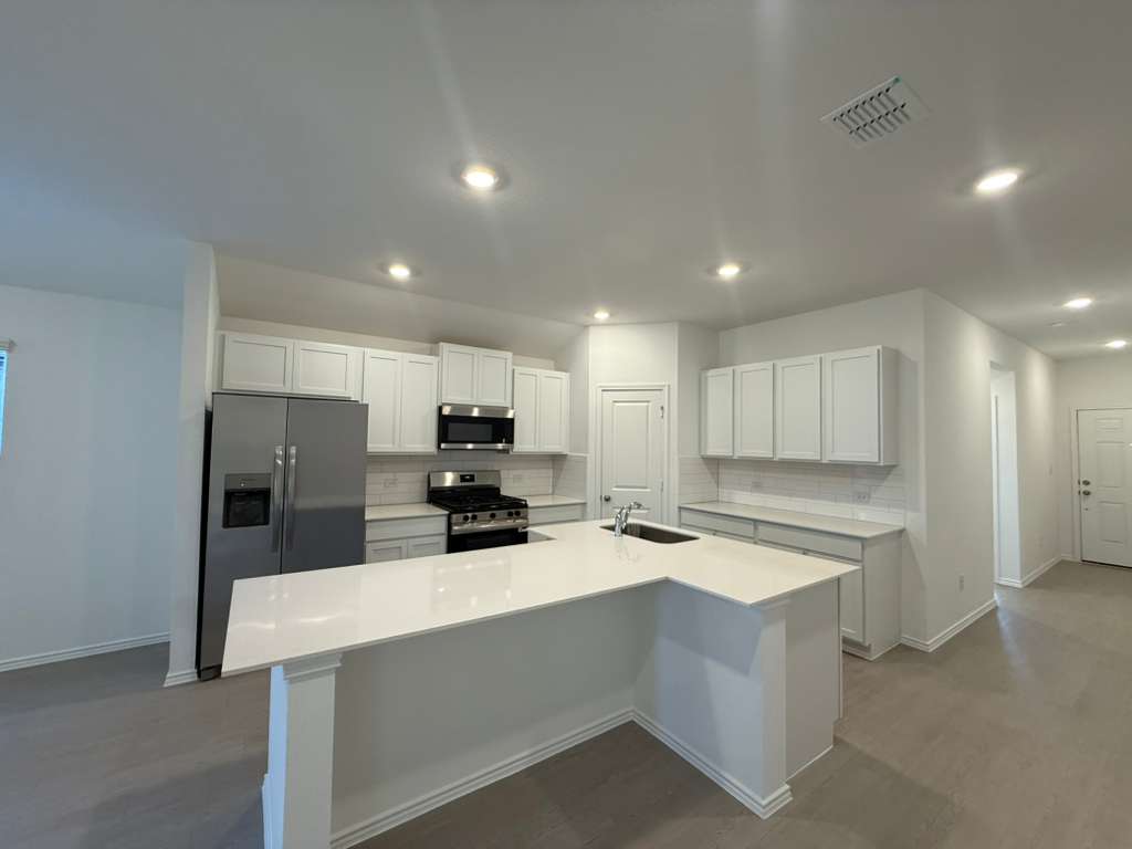 591 Sormonne Loop Kyle, TX 78640 - Photo 9 of 40 a kitchen with a refrigerator a stove top oven and white cabinets