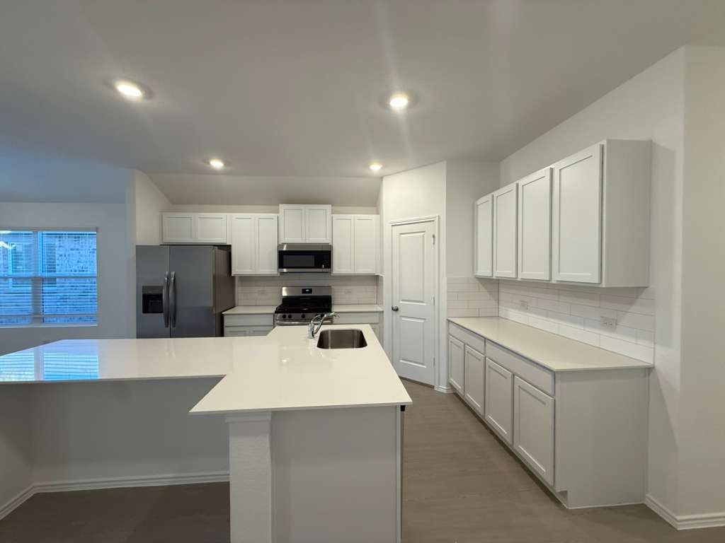 591 Sormonne Loop Kyle, TX 78640 - Photo 10 of 40 a kitchen with a sink a stove a refrigerator a counter top space and cabinets