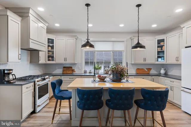 a kitchen with stainless steel appliances kitchen island granite countertop a sink a stove a refrigerator and island with wooden floor