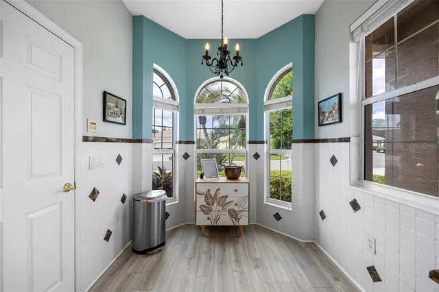 a view of a hallway with a dining table chairs a chandelier and wooden floor