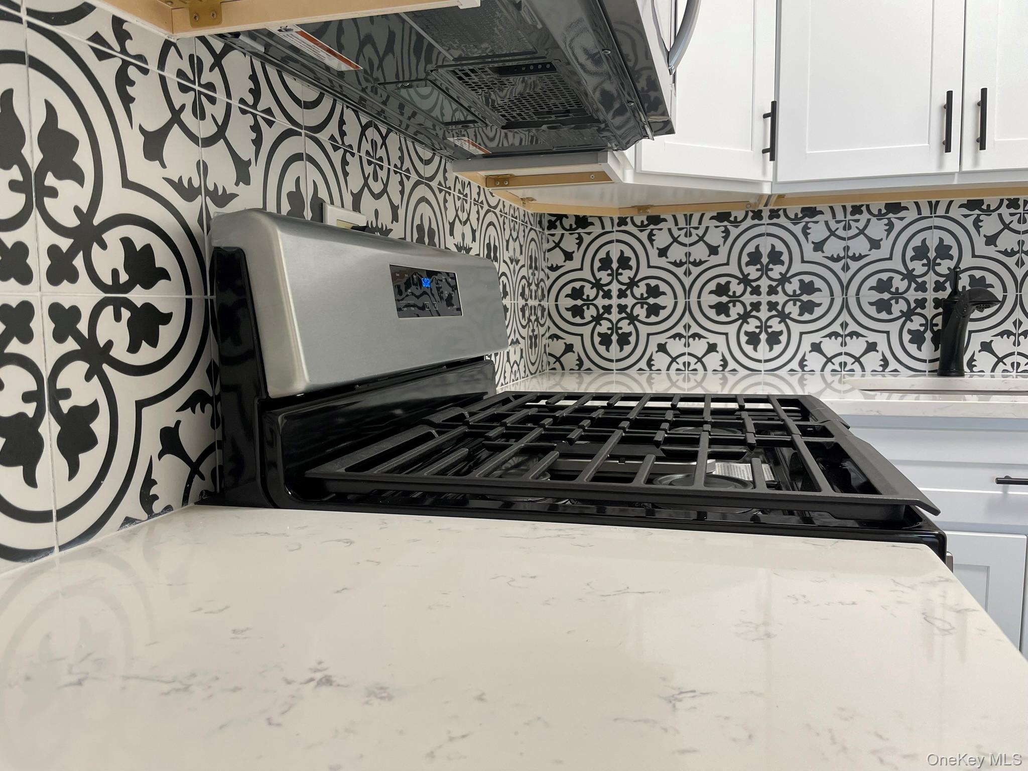301 West 110th Street, Unit 14F Manhattan, NY 10026 - Photo 7 of 18 Kitchen with white cabinets, gas stove, light stone counters, and decorative backsplash