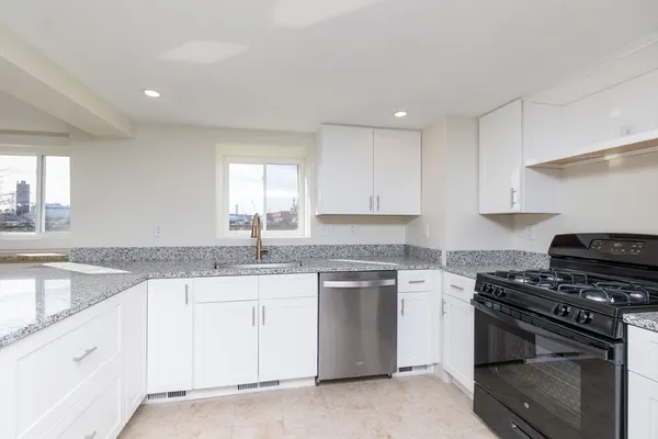 a kitchen with granite countertop white cabinets and stainless steel appliances