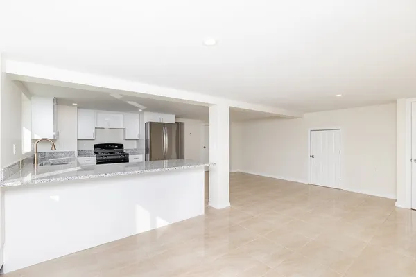 a view of a kitchen with kitchen island a sink wooden floor and living room view