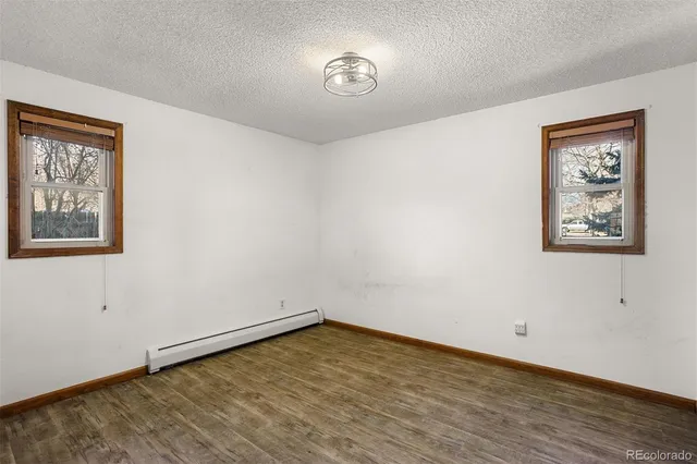 a view of an empty room with a window and wooden floor