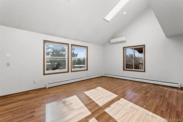 a view of an empty room with a window and wooden floor