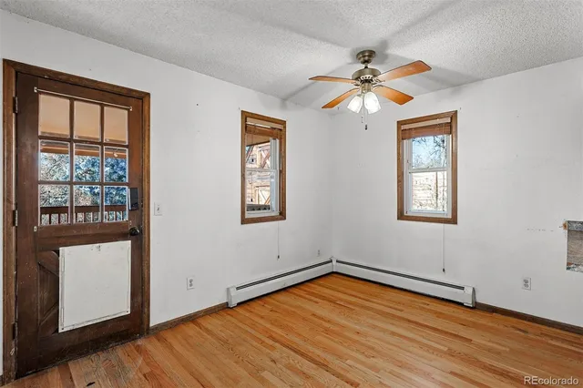 a view of empty room with wooden floor and fan