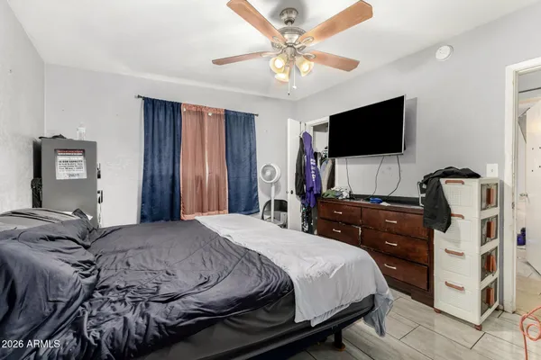 a bedroom with a bed a mirror on dresser and a flat screen tv