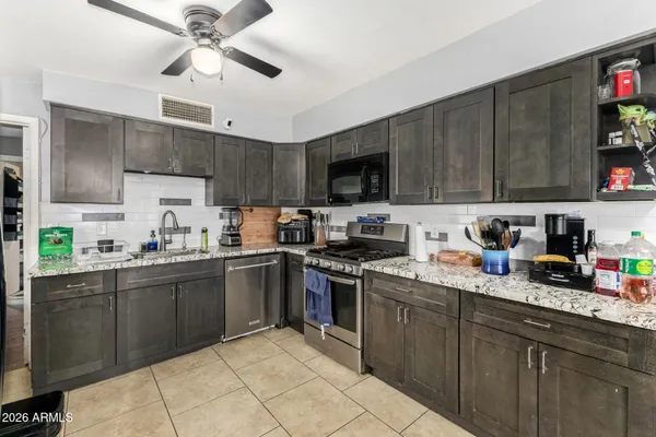 a kitchen with stainless steel appliances granite countertop a sink dishwasher a stove top oven a refrigerator and cabinets with wooden floor