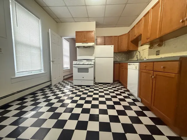 a kitchen with a checkered floor and white cabinets