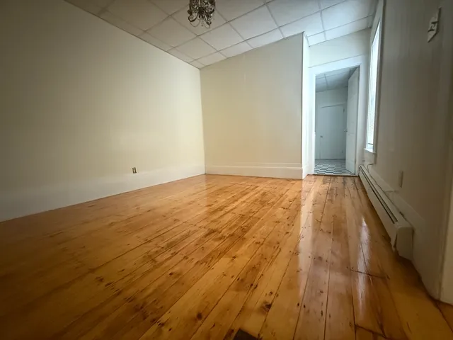 an empty room with wooden floor and fan