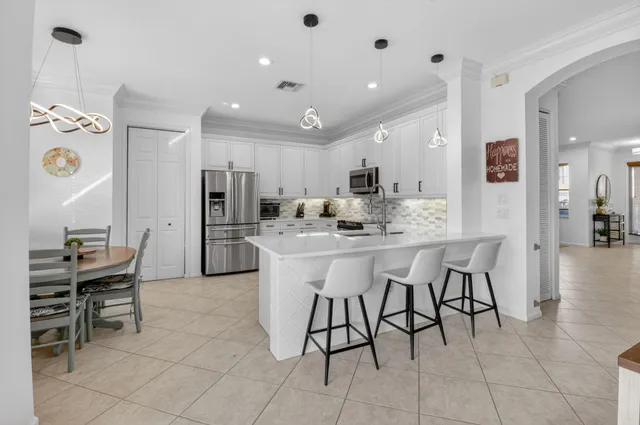 a kitchen with stainless steel appliances kitchen island granite countertop a table chairs and a refrigerator