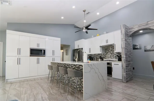 a kitchen with stainless steel appliances kitchen island granite countertop a refrigerator and a stove top oven