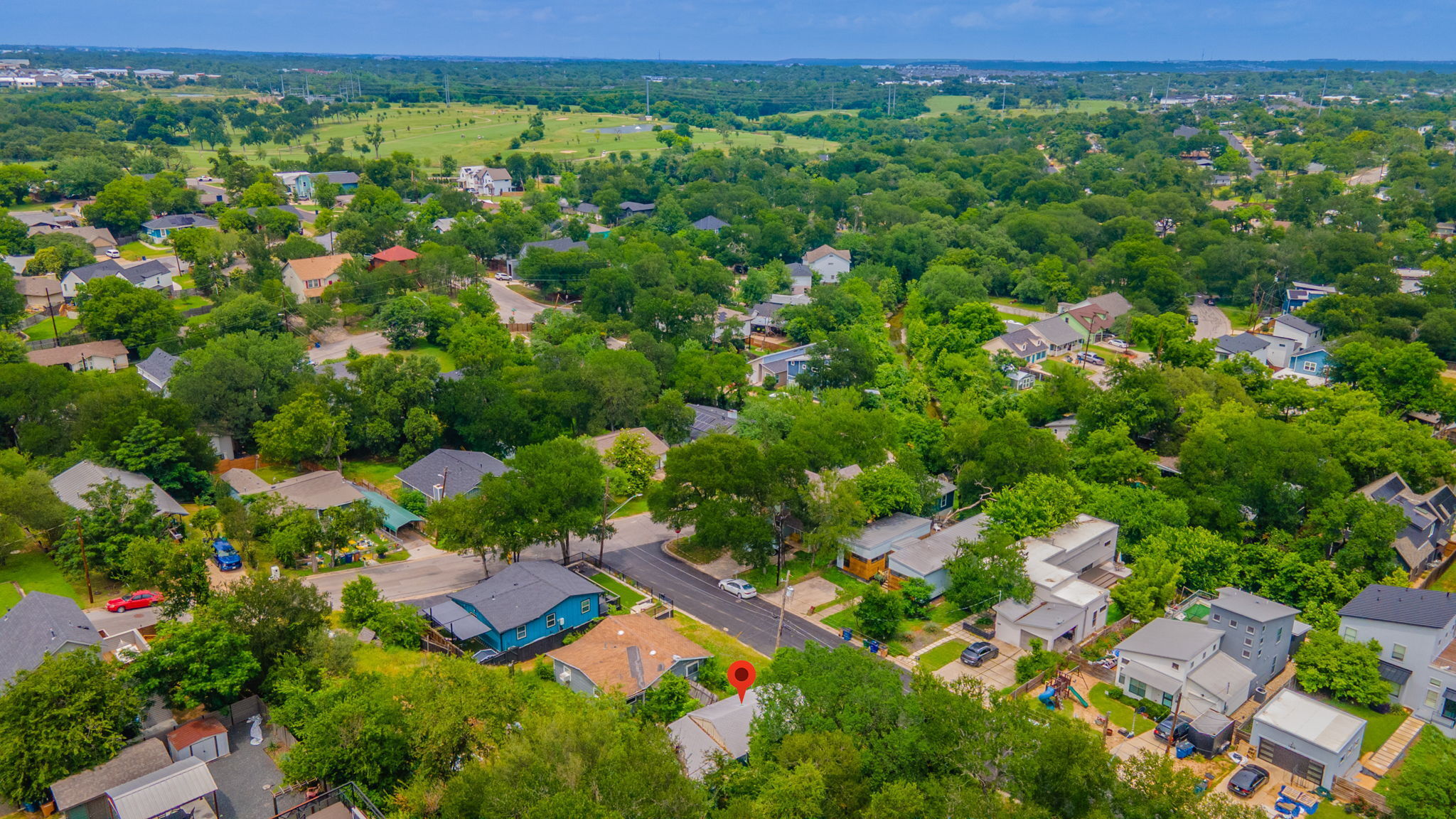 1408 Luna Street Austin, TX 78721 - Photo 5 of 5 An aerial perspective reveals a verdant neighborhood with a golf course beyond the tree line.