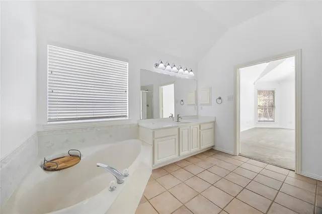 a spacious bathroom with a tub sink and mirror