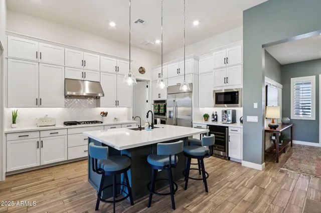 a kitchen with stainless steel appliances a white table chairs and a refrigerator