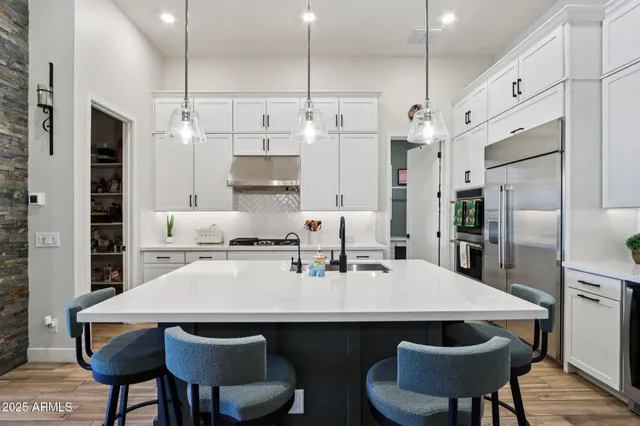 a kitchen with stainless steel appliances a stove a sink a microwave a refrigerator and cabinets