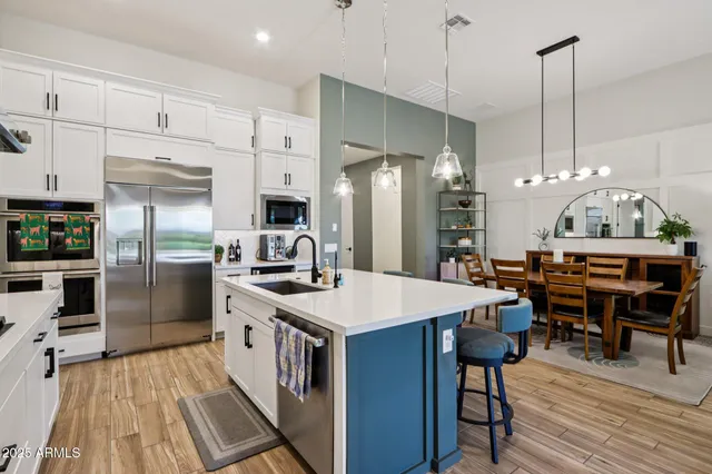 a kitchen with stainless steel appliances a table chairs stove and refrigerator