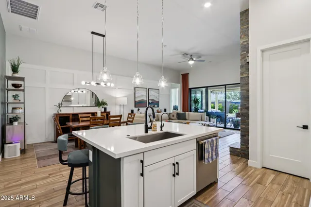 a kitchen with stainless steel appliances kitchen island granite countertop a refrigerator a stove a sink dishwasher and a dining table with wooden floor