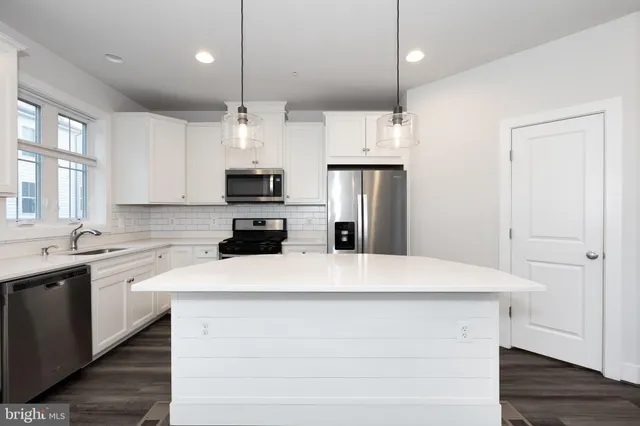a kitchen with kitchen island a sink stainless steel appliances and cabinets