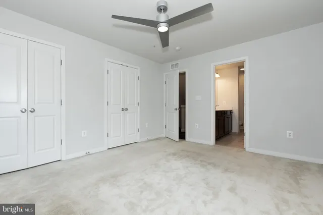 an empty room with closet and a ceiling fan