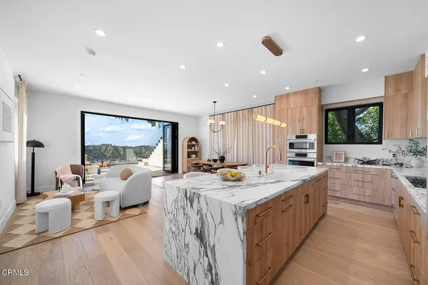 a large kitchen with stainless steel appliances lots of white furniture a sink dishwasher and a large mirror with wooden floor