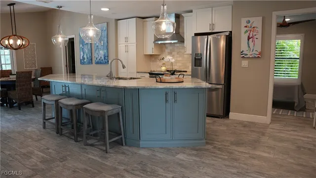 a kitchen with stainless steel appliances kitchen island granite countertop a refrigerator a sink a dining table and chairs