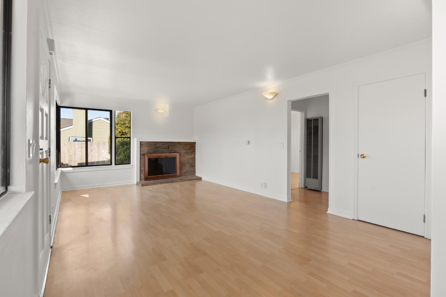 443 Monterey Road Pacifica, CA 94044 - Photo 8 of 26 an empty room with wooden floor fireplace and windows