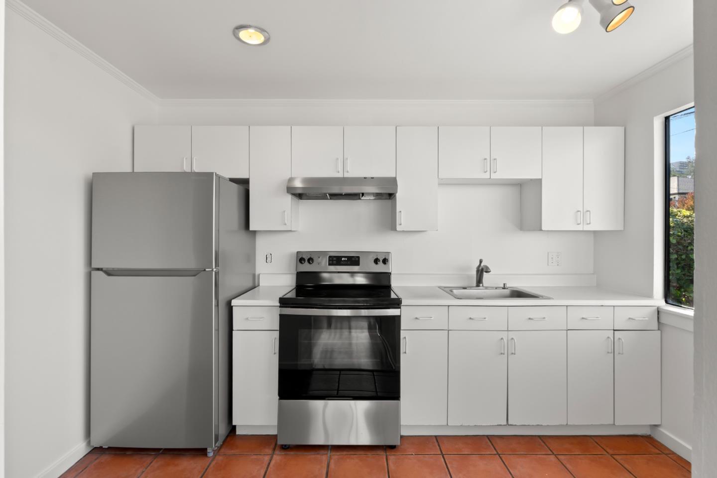 443 Monterey Road Pacifica, CA 94044 - Photo 9 of 26 a kitchen with a sink a refrigerator and white cabinets