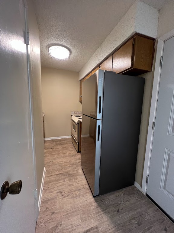 202 East 32nd Street, Unit 2 Austin, TX 78705 - Photo 4 of 22 a view of a refrigerator in kitchen and an empty room with wooden floor