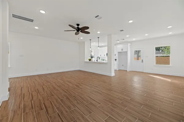 a view of empty room with wooden floor and fan