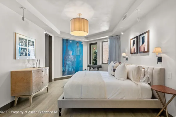 a bedroom with a bed and dresser with wooden floor