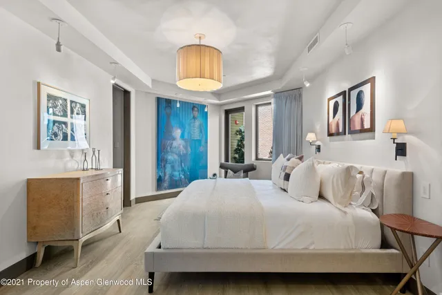 a bedroom with a bed and dresser with wooden floor