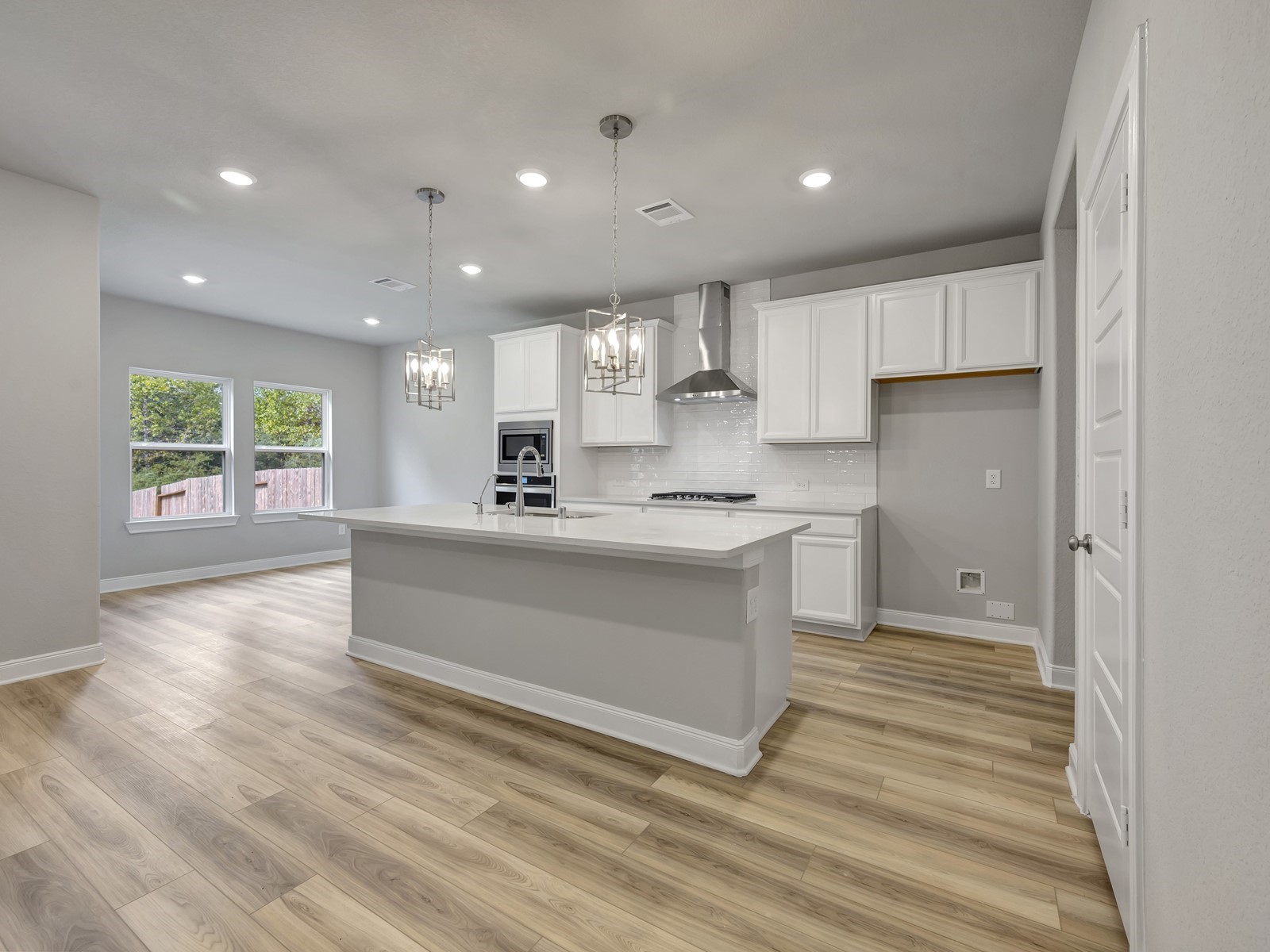 a large white kitchen with kitchen island a sink a stove and a refrigerator