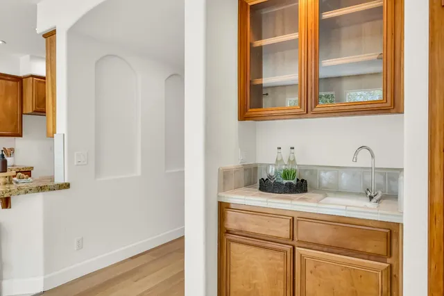 a view of a hallway with the couches and dining table with wooden floor