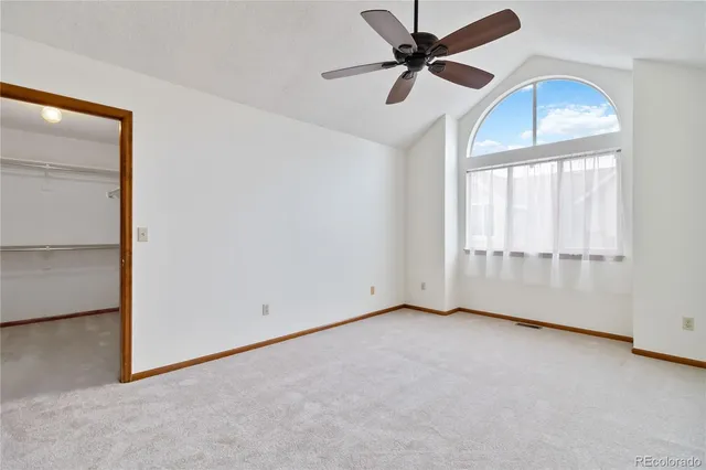 an empty room with chandelier fan and windows