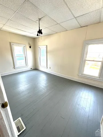 an empty room with wooden floor chandelier fan and windows