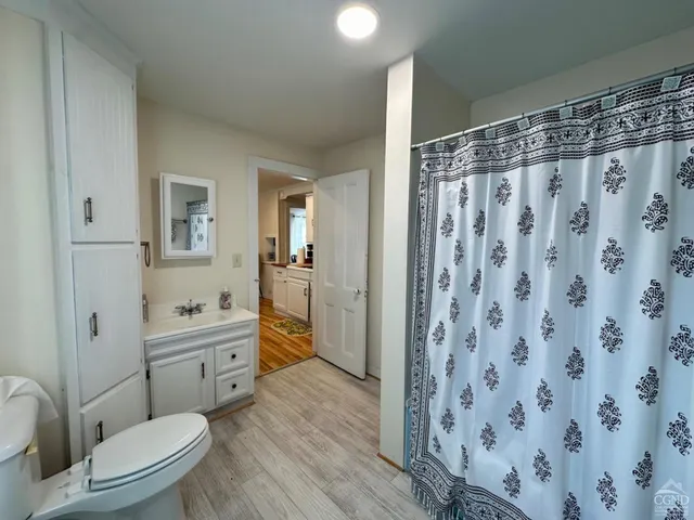a bathroom with a granite countertop sink a toilet a mirror a vanity and shower