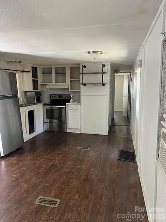 a view of a electric appliances in kitchen and empty room with wooden floor