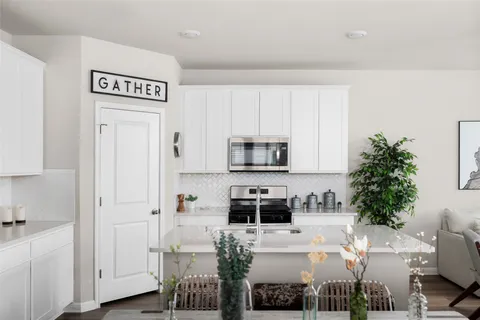 a white kitchen with stainless steel appliances a white table chairs and a refrigerator