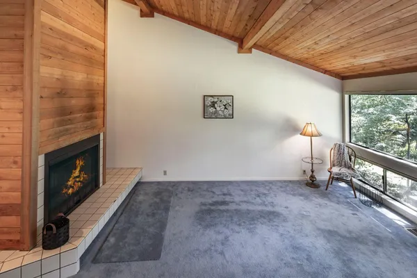 a view of an empty room with wooden floor fireplace and a window